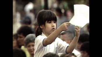 Movie still from “Narcos” (2015), created by Chris Brancato – A little girl holding something up to her face; Close Up shot, High angle