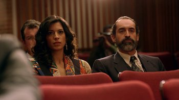 Movie still from “Narcos” (2015), created by Chris Brancato – A man and a woman are sitting in a theater; Medium shot, Low angle