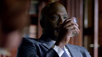 Movie still from “Narcos” (2015), created by Chris Brancato – A man in a suit drinking a glass of water; Close Up shot, Over the shoulder angle