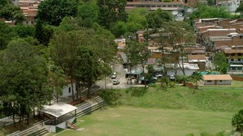 Movie still from “Narcos” (2015), created by Chris Brancato – An aerial view of a park with a car parked in the grass; Extreme Wide shot, High angle