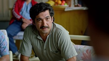 Movie still from “Narcos” (2015), created by Chris Brancato – A person sitting on a chair; Close Up shot, Over the shoulder angle