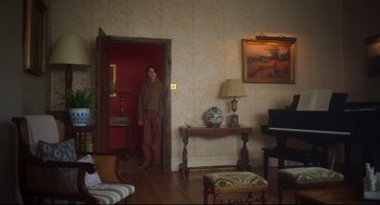 Movie still from “Men” (2022), directed by Alex Garland – A man standing in front of an open door in a living room; Wide shot, High angle