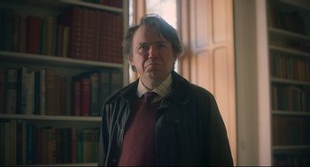 Movie still from “Men” (2022), directed by Alex Garland – A man standing in front of a book shelf; Medium shot, Low angle