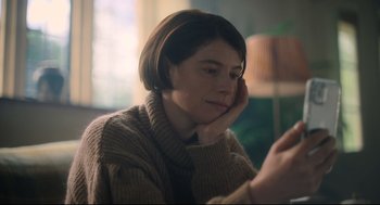 Movie still from “Men” (2022), directed by Alex Garland – A woman sitting in front of a mirror looking at her cell phone; Close Up shot, Over the shoulder angle