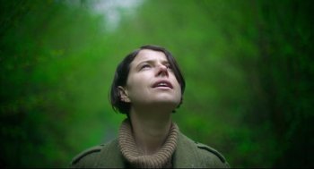 Movie still from “Men” (2022), directed by Alex Garland – A woman looking up at the sky in a wooded area; Close Up shot, Low angle