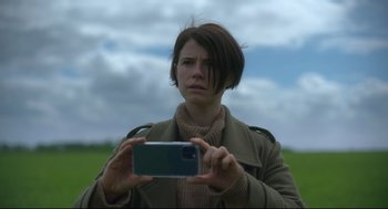 Movie still from “Men” (2022), directed by Alex Garland – A woman taking a picture with her cell phone; Close Up shot, Low angle