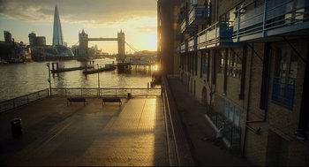Movie still from “Men” (2022), directed by Alex Garland – The sun is setting over a city with a bridge in the background; Extreme Wide shot, High angle