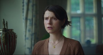 Movie still from “Men” (2022), directed by Alex Garland – A woman with short black hair wearing a brown sweater; Close Up shot, Low angle