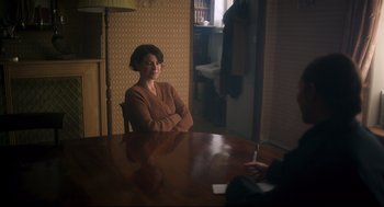 Movie still from “Men” (2022), directed by Alex Garland – A woman sitting at a wooden table in front of a man; Medium shot, Over the shoulder angle