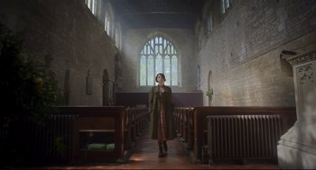 Movie still from “Men” (2022), directed by Alex Garland – A woman standing in the middle of an aisle of a church; Wide shot, Low angle