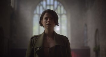 Movie still from “Men” (2022), directed by Alex Garland – A woman standing in front of a stained glass window; Close Up shot, Low angle