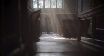 Movie still from “Men” (2022), directed by Alex Garland – A man standing in the sunlight in a church; Wide shot, Low angle