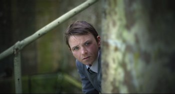 Movie still from “Men” (2022), directed by Alex Garland – A man in a suit leaning against a tree; Close Up shot, High angle