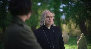 Movie still from “Men” (2022), directed by Alex Garland – A man with long white hair is listening to music while standing next to another man; Close Up shot, Over the shoulder angle