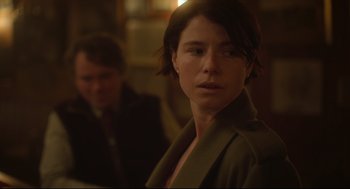 Movie still from “Men” (2022), directed by Alex Garland – A woman with short brown hair wearing a jacket; Close Up shot, Over the shoulder angle