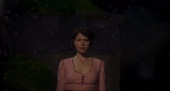 Movie still from “Men” (2022), directed by Alex Garland – A woman in a pink dress standing in the dark; Medium shot, Low angle
