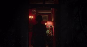 Movie still from “Men” (2022), directed by Alex Garland – A person standing in a dark room with a lamp; Wide shot, Over the shoulder angle