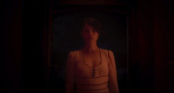 Movie still from “Men” (2022), directed by Alex Garland – A woman standing in front of a window at night; Medium shot, Low angle