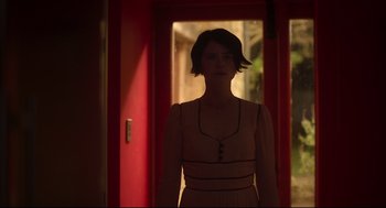 Movie still from “Men” (2022), directed by Alex Garland – A woman standing in front of an open door; Medium shot, Low angle