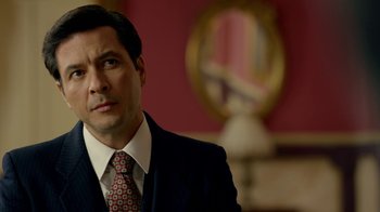 Movie still from “Narcos” (2015), created by Chris Brancato – A person wearing a suit and tie; Close Up shot, Over the shoulder angle