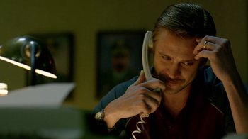 Movie still from “Narcos” (2015), created by Chris Brancato – A man talking on a phone while sitting in a room; Close Up shot, Low angle