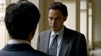 Movie still from “Narcos” (2015), created by Chris Brancato – A man wearing a suit and tie looking at himself in the mirror; Close Up shot, Over the shoulder angle