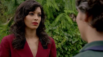 Movie still from “Narcos” (2015), created by Chris Brancato – A woman in a red dress talking to a man in a red suit; Close Up shot, Over the shoulder angle