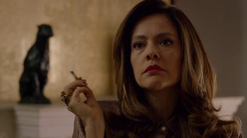 Movie still from “Narcos” (2015), created by Chris Brancato – A person holding a cigarette in her hand; Close Up shot, Over the shoulder angle