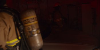 Movie still from “Midsommar” (2019), directed by Ari Aster – A fire hydrant in a room with a fire fighter in the background; Extreme Close Up shot, Low angle