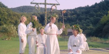 Movie still from “Midsommar” (2019), directed by Ari Aster – A group of people dressed in all white holding sticks; Wide shot, High angle