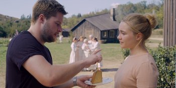 Movie still from “Midsommar” (2019), directed by Ari Aster – A man and a woman holding a piece of cake; Medium shot, Over the shoulder angle
