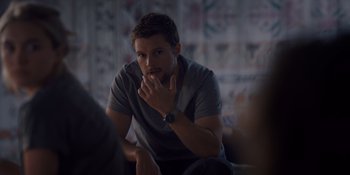 Movie still from “Midsommar” (2019), directed by Ari Aster – A man sitting in front of a wall with his hand under his chin; Close Up shot, Over the shoulder angle