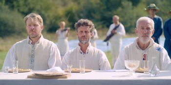Movie still from “Midsommar” (2019), directed by Ari Aster – A group of people sitting at a table with food; Medium shot, Over the shoulder angle