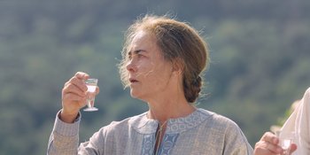 Movie still from “Midsommar” (2019), directed by Ari Aster – A woman holding a wine glass in her right hand; Close Up shot, Over the shoulder angle