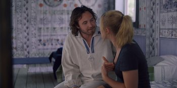 Movie still from “Midsommar” (2019), directed by Ari Aster – A man and a woman sitting on a couch talking to each other; Medium shot, Over the shoulder angle