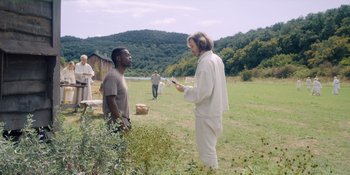 Movie still from “Midsommar” (2019), directed by Ari Aster – Two people in a field talking to each other; Wide shot, Over the shoulder angle