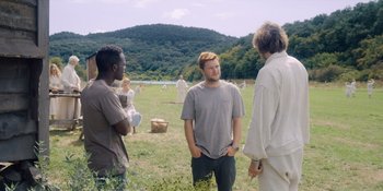 Movie still from “Midsommar” (2019), directed by Ari Aster – A group of people standing in the grass; Wide shot, Over the shoulder angle