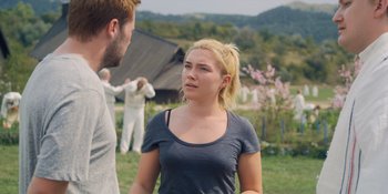 Movie still from “Midsommar” (2019), directed by Ari Aster – A woman standing next to a man in front of a building; Medium shot, Over the shoulder angle
