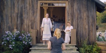 Movie still from “Midsommar” (2019), directed by Ari Aster – Two women are standing in front of a building; Wide shot, Over the shoulder angle