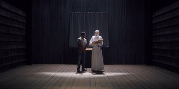 Movie still from “Midsommar” (2019), directed by Ari Aster – A man standing next to an old man in a white robe; Wide shot, Low angle