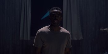 Movie still from “Midsommar” (2019), directed by Ari Aster – A man standing in front of a wall with lights; Medium shot, Low angle