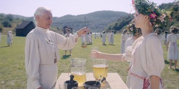 Movie still from “Midsommar” (2019), directed by Ari Aster – Two women in white clothes are drinking lemonade; Medium shot, Over the shoulder angle