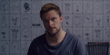 Movie still from “Midsommar” (2019), directed by Ari Aster – A person wearing a t - shirt; Close Up shot, Over the shoulder angle