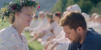 Movie still from “Midsommar” (2019), directed by Ari Aster – A man and a woman sitting in front of each other on a field; Close Up shot, Over the shoulder angle