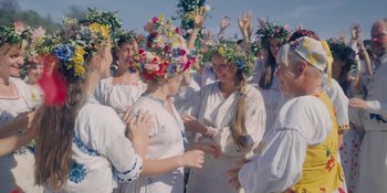 Movie still from “Midsommar” (2019), directed by Ari Aster – A group of women wearing flower crowns and holding hands; Medium shot, High angle