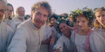Movie still from “Midsommar” (2019), directed by Ari Aster – A group of young people wearing floral garb and posing for a picture; Medium shot, Low angle