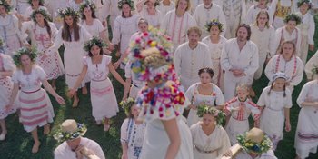 Movie still from “Midsommar” (2019), directed by Ari Aster – A group of people wearing white clothes and flower wreaths on their heads; Wide shot, High angle