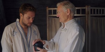Movie still from “Midsommar” (2019), directed by Ari Aster – A man and a man holding something in their hands; Close Up shot, Over the shoulder angle