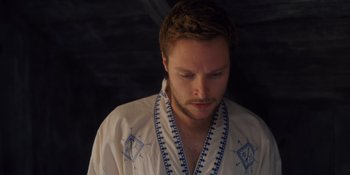 Movie still from “Midsommar” (2019), directed by Ari Aster – A man in a white shirt is looking down at his face; Close Up shot, Low angle