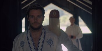 Movie still from “Midsommar” (2019), directed by Ari Aster – A man standing in front of another man in a white robe; Medium shot, Low angle